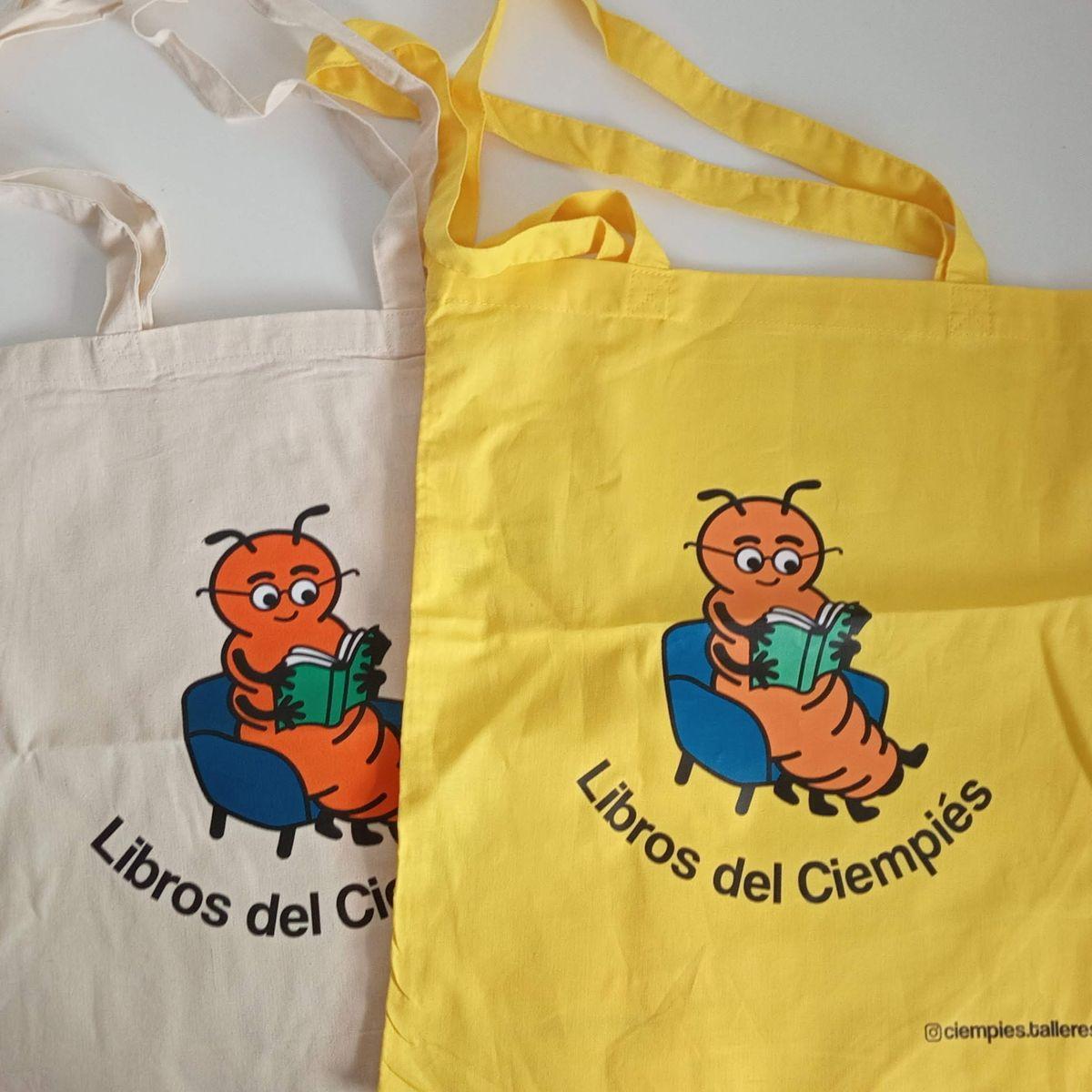Una foto que muestra dos tote bags (una en amarillo y otra en natural) con la mascota de Ciempiés y la leyenda Libros del Ciempiés