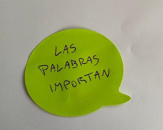 Fotografía que muestra sobre una hoja de papel blanco un post-it en forma de globo de diálogo y de color amarillo fluo que tiene escrito lo siguiente: Las palabras importan