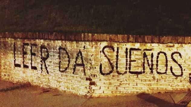 Fotografía de una pintada sobre una pared de ladrillos que dice «leer da sueños». Crédito: Erika Cosenza